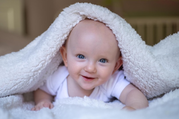 Bebê sorridente olhando para a câmera sob uma toalha branca