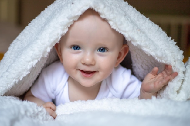 Bebê sorridente olhando para a câmera sob uma toalha branca