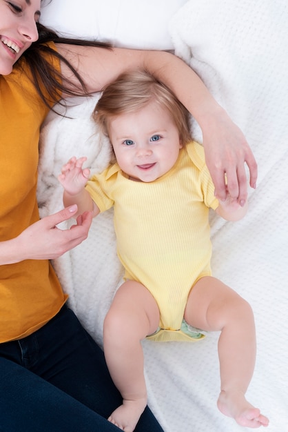 Foto bebê sorridente posando ao lado da mãe