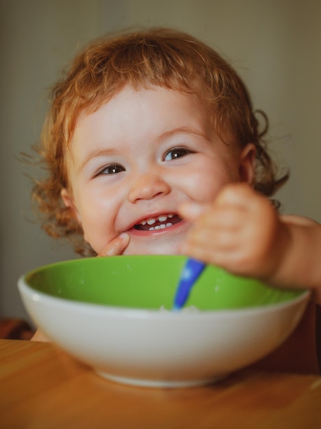 Bebé sosteniendo una cuchara en su boca niño feliz comiéndose a sí mismo con una cuchara lanzando a un niño comiendo comida