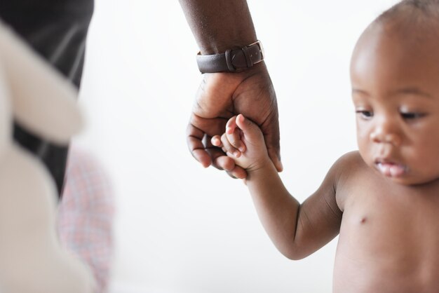 Bebé sosteniendo la mano de su padre