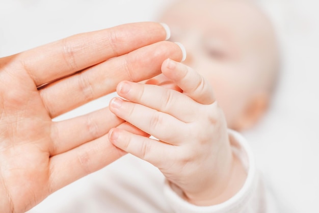 El bebé sostiene con ambas manos La mano de la madre toca y la examina El vínculo emocional entre la madre y el niño Desarrollo de habilidades motoras de las manos Amor cuidado familiar