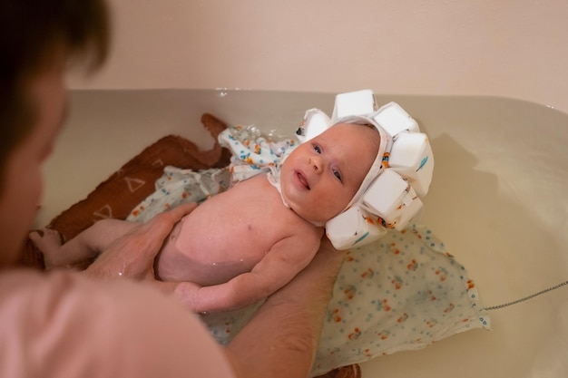 Foto bebê tomando banho com chapéu de natação especial. pai segurando-a por segurança