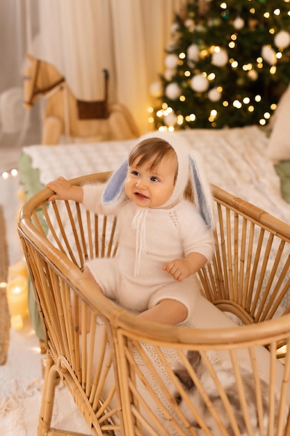 bebé en un traje de conejo en una cuna en el fondo del árbol de Navidad