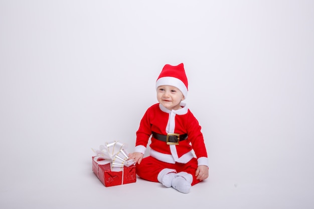 Un bebé en un traje de Santa Claus sobre un fondo blanco.