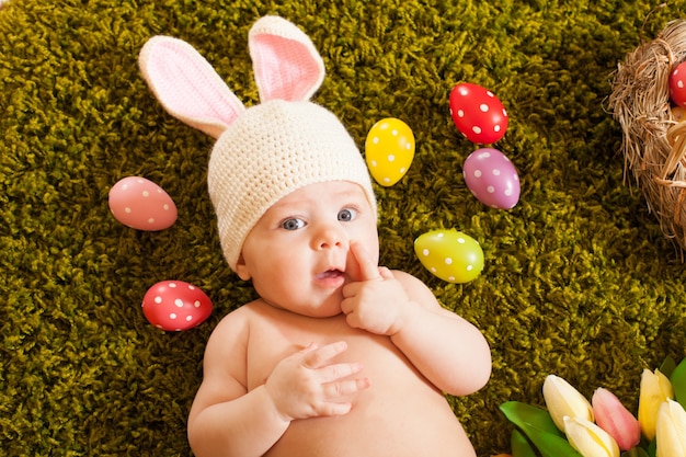 Bebé de tres meses acostado sobre la alfombra de hierba como un conejito de Pascua