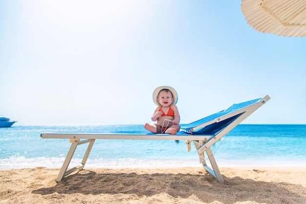 Bebé en una tumbona cerca del mar con un sombrero