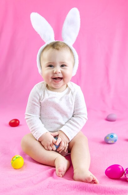 Bebê vestido como um coelho com ovos de Páscoa para o feriado de Páscoa