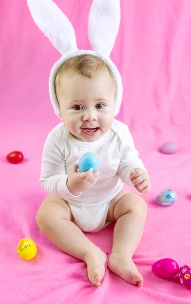 Bebê vestido como um coelho com ovos de Páscoa para o feriado de Páscoa