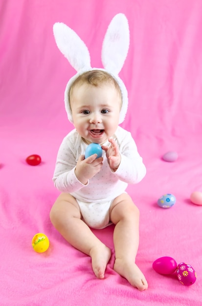 Bebê vestido como um coelho com ovos de Páscoa para o feriado de Páscoa