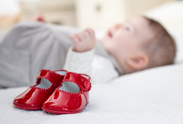 Bebé zapatos rojos y nena acostada en el fondo