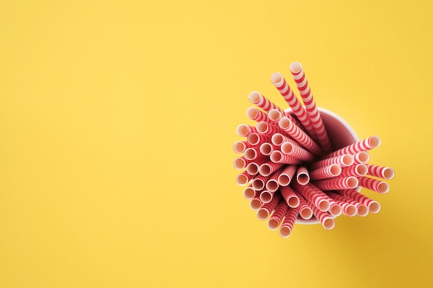 Bebederos rojos y marrones hechos de papel y maicena, material biodegradable y vasos de papel ecológico sobre fondo amarillo y gris color tendencia 2021. Cero desperdicio y concepto libre de plástico. Vista superior.