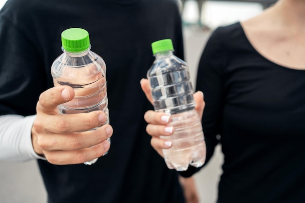 Beben agua limpia de dos botellas de plástico.