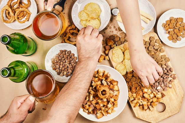 Bebendo cerveja. Mesa cheia de petiscos de cerveja