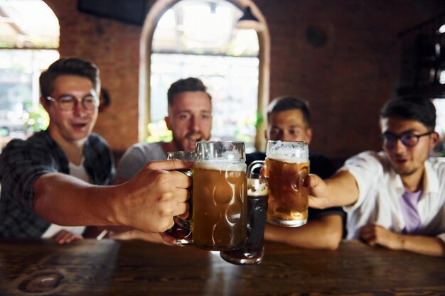 Bebendo cerveja Pessoas em roupas casuais sentadas no pub