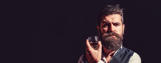 Bebendo uísque Retrato de homem com barba grossa Macho bebendo Homem barba segura conhaque de vidro Bebida barbuda conhaque Homem segurando um copo de uísque