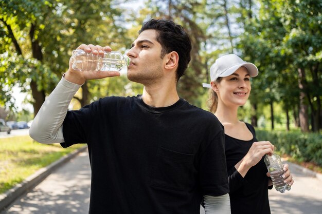 Beber água é um estilo de vida saudável um homem e uma mulher correndo estão praticando esportes