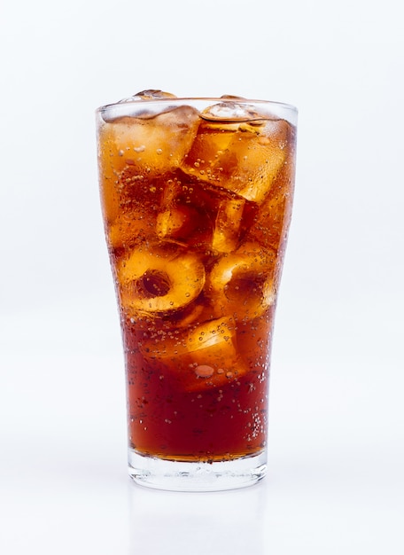 Beber cola con hielo en vaso sobre fondo blanco.