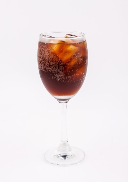 Beber cola con hielo en vaso sobre fondo blanco.