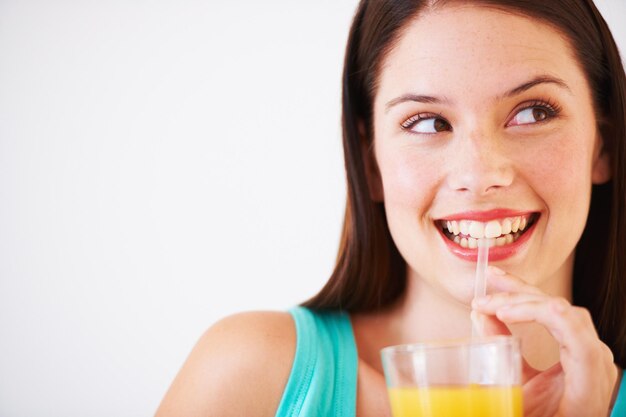 Foto beber feliz y cara de mujer con jugo para nutrición bienestar e hidratación en el estudio bebida sonrisa y persona sedienta con mezcla de frutas para vitaminas desintoxicación y dieta en fondo blanco