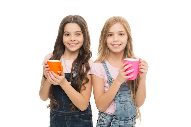 Beber leche para una buena salud. Niños lindos tomando un trago de té con leche. Niños pequeños sosteniendo tazas con bebidas de leche tibia. Niñas disfrutando de la leche caliente.