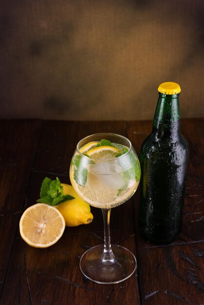 Beber en un vaso con limón y menta vaso y botella en la mesa vintage fondo marrón