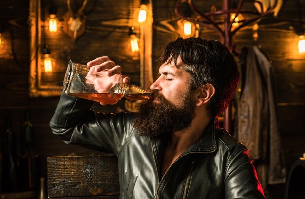 Foto bebericando degustação de uísque, saboreando o retrato de um homem bonito com brutalidade de barba e masculino