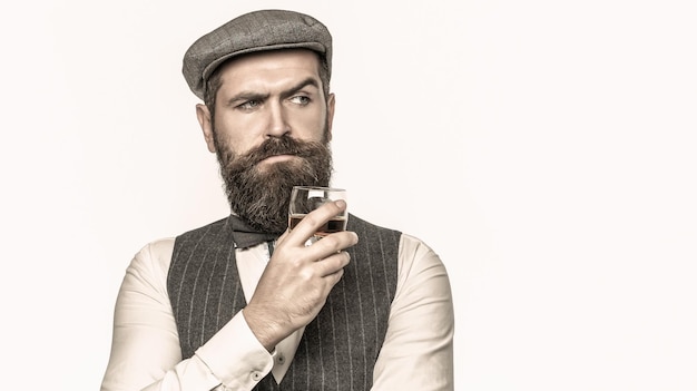 Bebericando o melhor uísque. Retrato de homem com barba espessa. Beber macho. Homem rico elegante segurando um copo de whisky velho. Cavalheiro barbudo bebe conhaque.