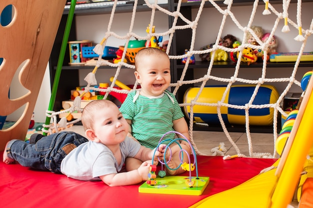 Bebês de dois meninos espertos brincando com um brinquedo na sala de jogos