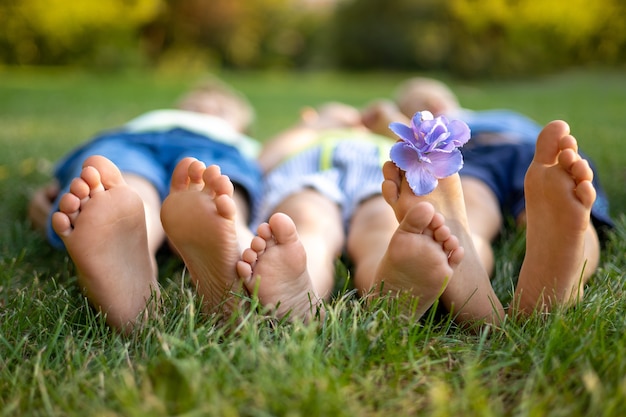 Bebês deitados na grama do parque no verão, close-up das pernas das crianças