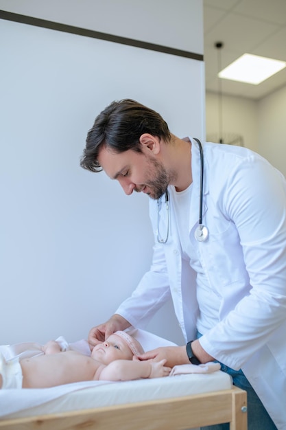 Bebês examinando. Pediatra masculino examinando um bebê e parecendo concentrado