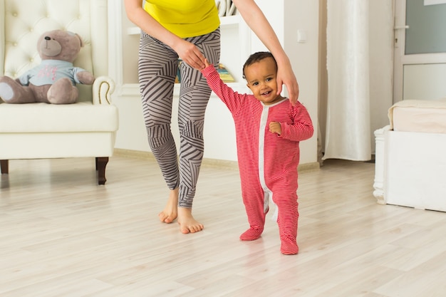 Bebezinho aprendendo a andar, a mãe está segurando suas mãos.