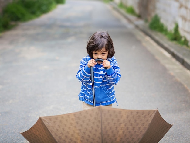 Bebezinho bonito brincando com guarda-chuva ao ar livre