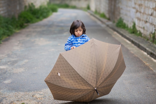 Bebezinho bonito brincando com guarda-chuva ao ar livre