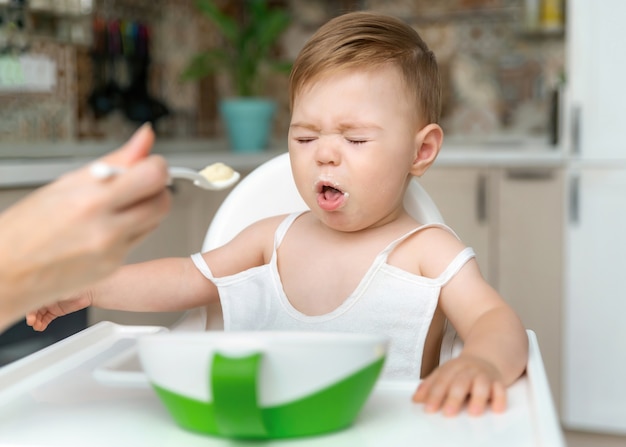 Bebezinho charmoso de 811 meses não quer comer mingau na colher com a mãe em casa