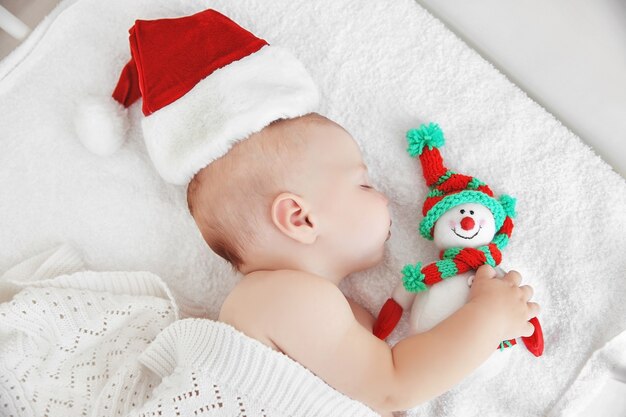 Bebezinho com chapéu de natal na cama branca