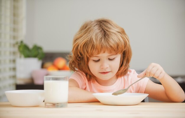 Bebezinho com fome saudável comendo sopa do prato com colher