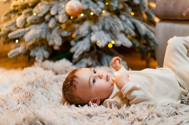 Bebezinho deitado perto da árvore de Natal Criança pequena celebra o natal em casa Conceito de Natal e Ano Novo