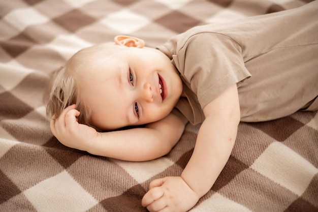 Bebezinho em roupas bege claro brincando em uma cama de luz em casa no quarto casa conforto felicidade da maternidade bebê em casa