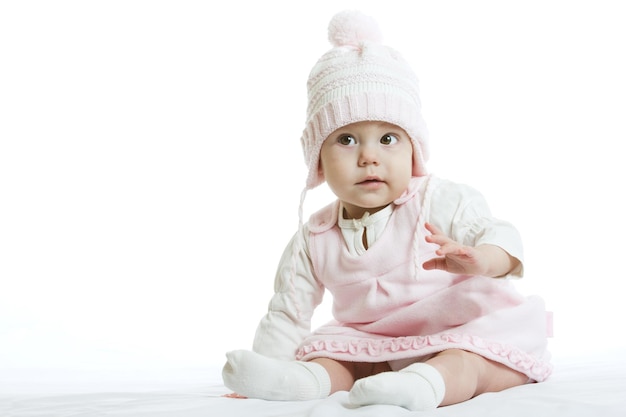 Bebezinho em roupas de inverno de malha fechando o rosto com gorro de malha na cama no quarto azul novo conceito de proteção de família e bebê