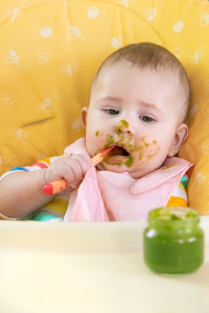 Bebezinho está comendo purê de vegetais de brócolis. Foco seletivo. Pessoas.