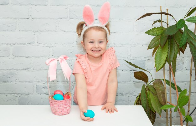 Bebezinho fofo com orelhas de coelho no dia da Páscoa. Menina com ovos de Páscoa