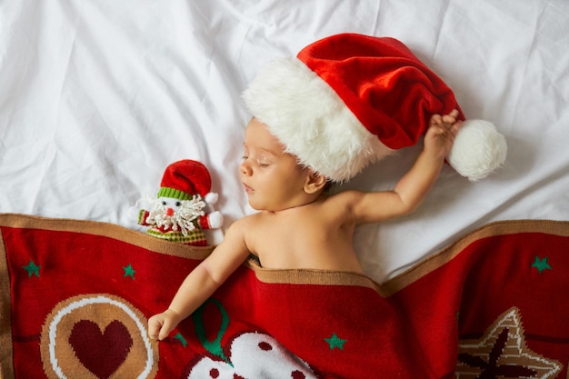 Bebezinho recém-nascido com chapéu de Papai Noel debaixo do cobertor