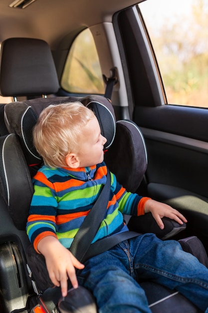 Bebezinho sentado na cadeirinha do carro apertou o cinto de segurança no carro. Segurança para cadeirinha de carro infantil