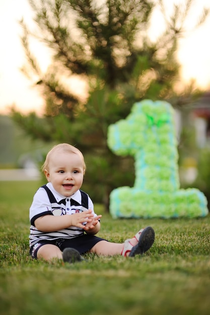 Bebezinho sentado na grama e sorri em seu primeiro aniversário