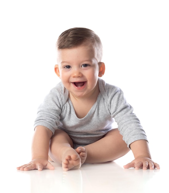 Bebezinho sorridente em bodysuit sentado com os pés descalços no chão isolado no branco