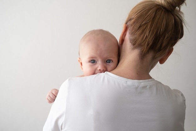 Bebezinhos meninos enfrentam nas mãos da mãe. olhos azuis. família feliz. amor sem fim. mãe de enfermagem. relaxe com o filho pequeno. em casa. amor. doce. ternura.