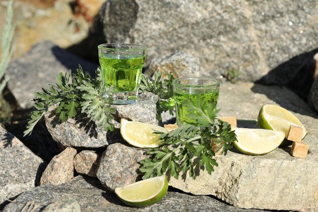 bebida de absenta verde sobre fondo negro con azúcar y lima. Fondo de piedras