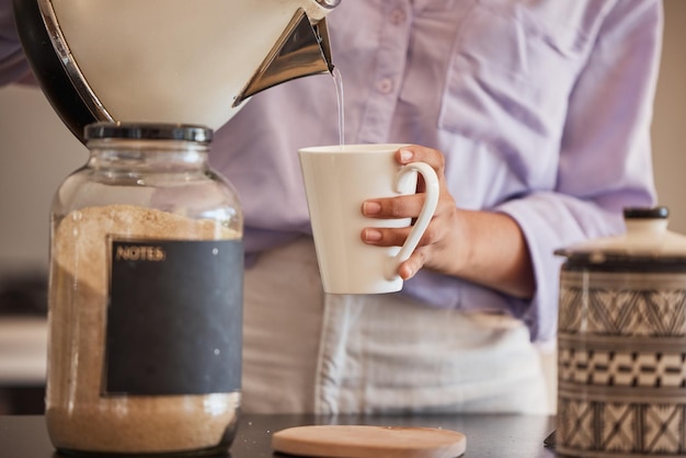 Bebida de agua y mujer hacen café en la cocina para motivar energía y cafeína en la mañana Cafetería de estilo de vida y primer plano de las manos vertiendo agua de la tetera a la taza para bebidas calientes espresso y té