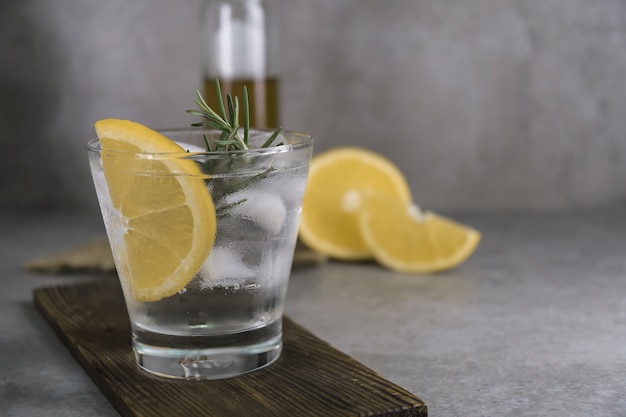 Bebida alcohólica gin tonic cocktail con limón, romero y hielo